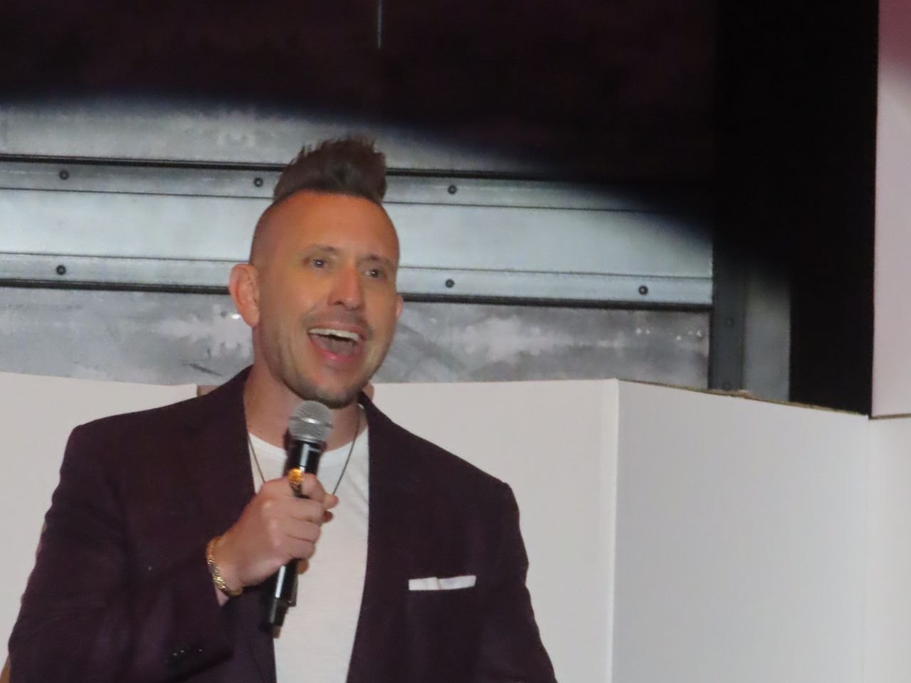 Joshua B. Lee speaking on stage with microphone